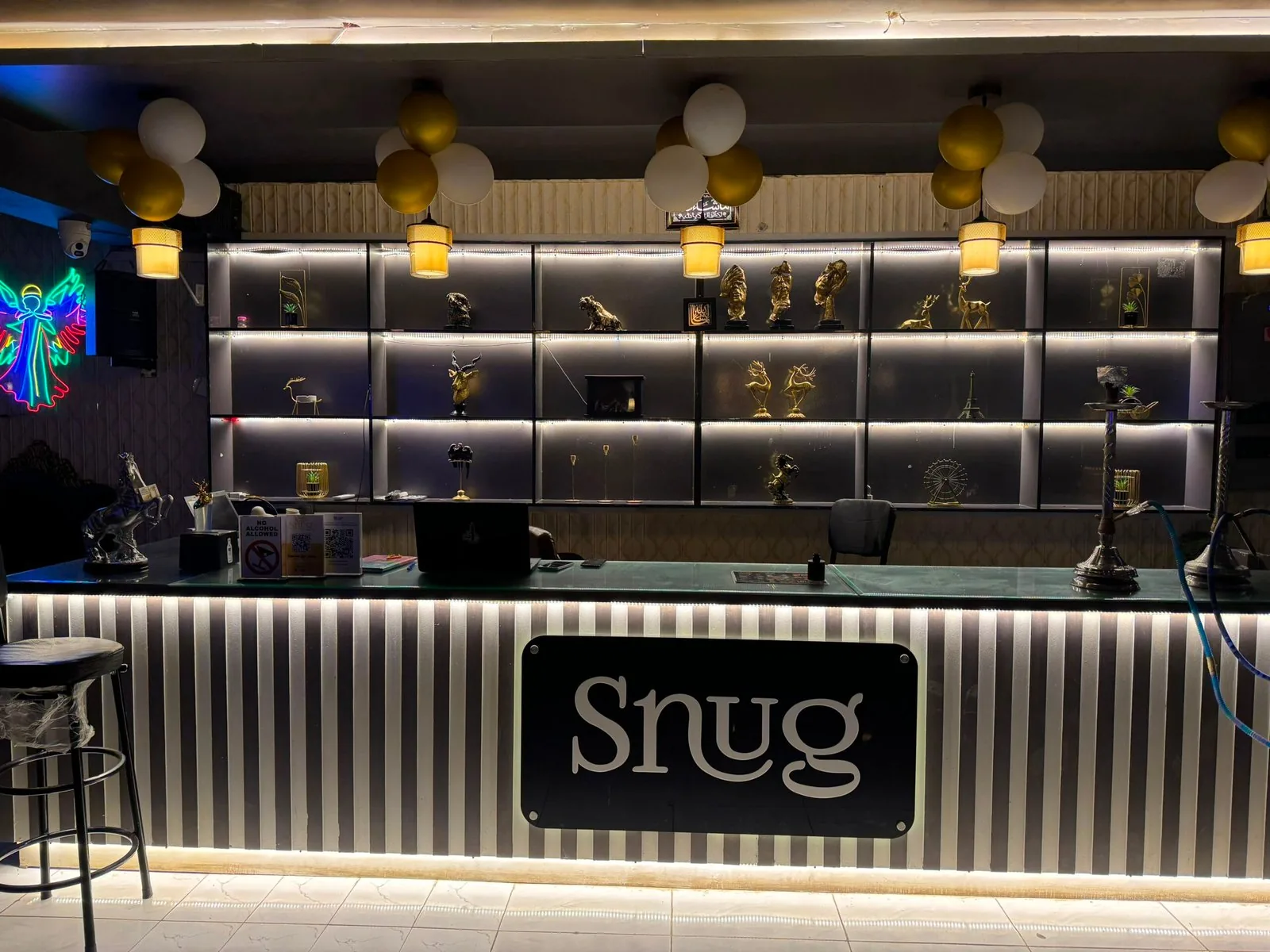 The Snug bar — backlit gold shelves and the black-and-white counter